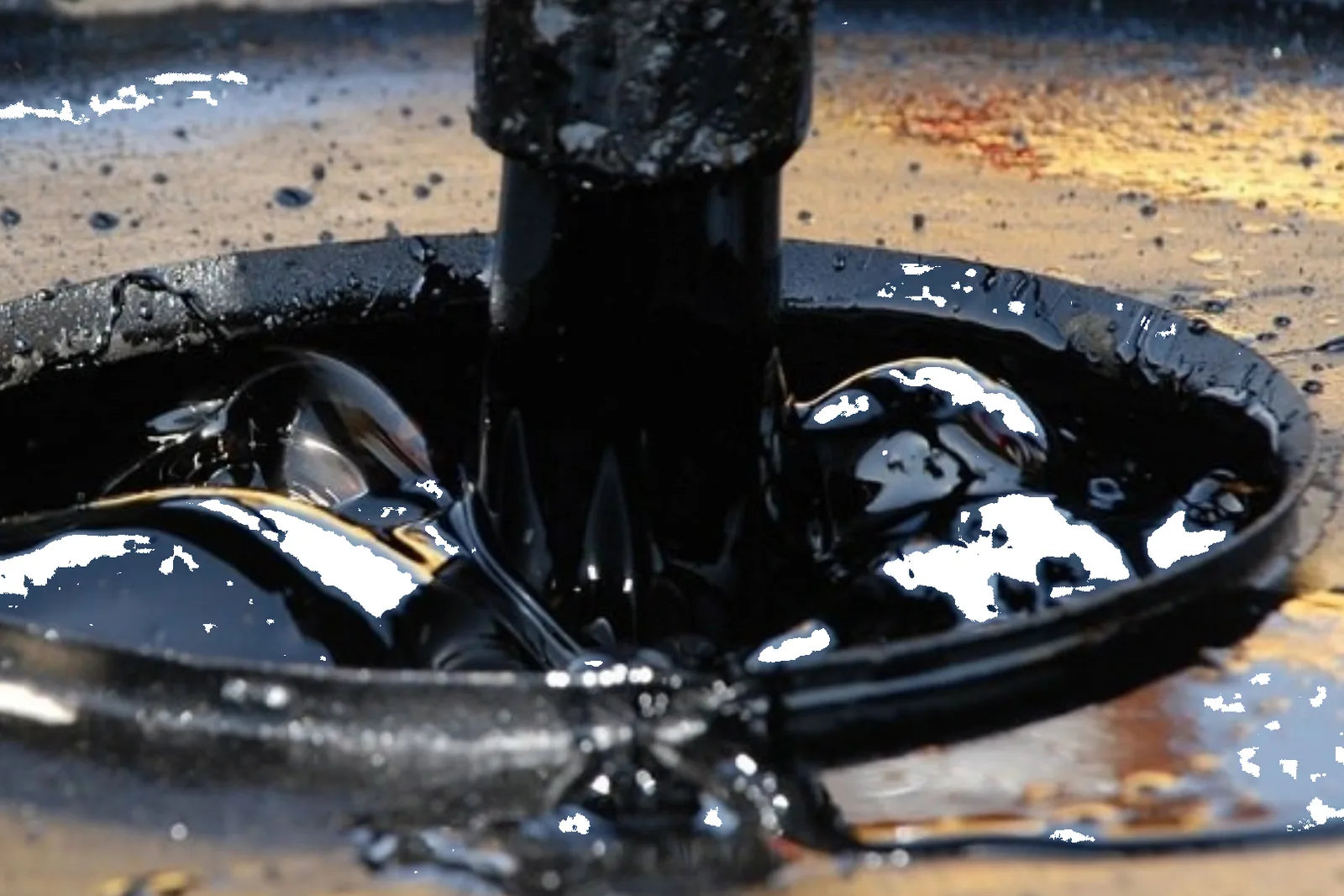 Bitumen 60/70 penetration grade pouring into a metal drum, showing a viscous, glossy black texture.